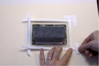 7. Coloca la obra en la trasera y fíjala usando cinta de papel o lino con adhesivo al agua.
