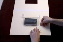 3. Marca la posición de las esquinas superiores con un papel pero no las pegues aún. Asegura las esquinas inferiores en su sitio usando cinta con adhesivo al agua de papel o lino. Retira la obra.